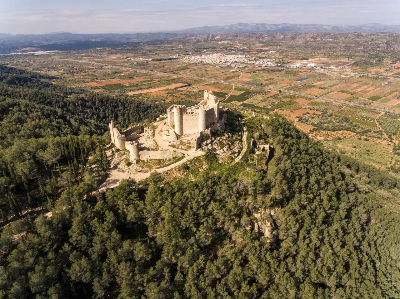 Castillo de Xivert, con vistas a Alcossebre y su ermita. Un paisaje de bosques y campos.