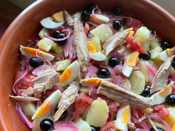 Deliciosa ensalada campera con patatas, huevo duro, atún, aceitunas negras y cebolla morada. ¡Un plato fresco y completo!