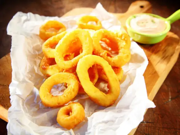 Crujientes calamares a la andaluza, dorados y listos para mojar en una cremosa salsa.