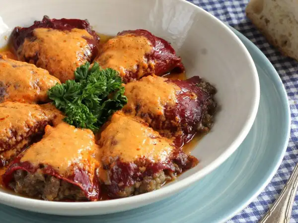 Pimientos rellenos de carne de la abuela, cubiertos con una cremosa salsa y decorados con perejil fresco. Un plato casero que evoca recuerdos.