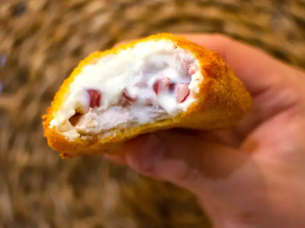 Pechuga villaroy crujiente por fuera, jugosa por dentro, con trocitos de jamón y bechamel cremosa.