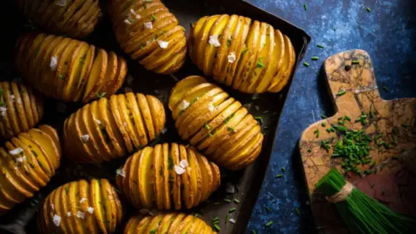 Patatas asadas doradas y crujientes, cortadas en láminas finas y espolvoreadas con sal marina y cebollino fresco. ¡Un placer para la vista y el paladar!