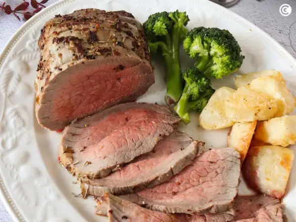 Jugoso roast beef cortado en rodajas, acompañado de brócoli al vapor y patatas asadas crujientes. Un festín para los sentidos.