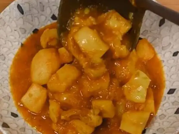 Un plato de papas con choco en una salsa naranja.