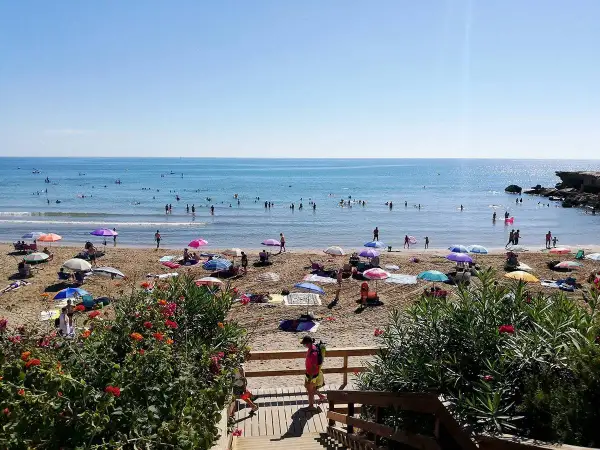 Playa llena de gente disfrutando del sol y el mar. ¡Un día perfecto para saber qué hacer en Alcossebre!