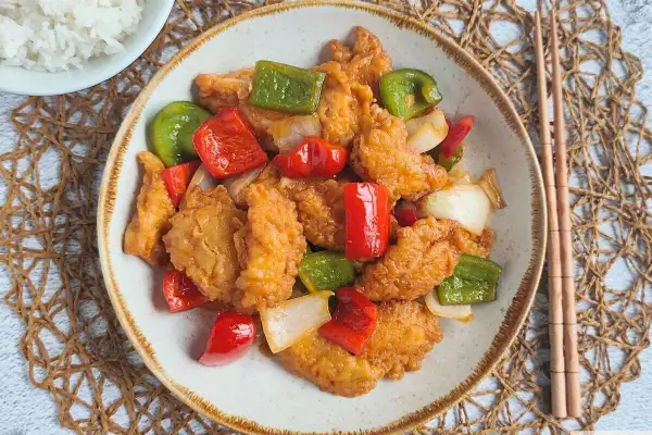 Saborea este delicioso pollo agridulce, crujiente por fuera y tierno por dentro, con pimientos y cebolla. ¡Un festín para tus sentidos!