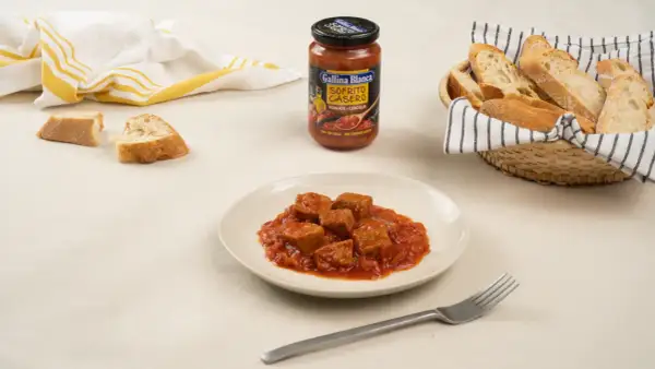 Sabroso atún con tomate en un plato, acompañado de pan y un sofrito casero de Gallina Blanca.