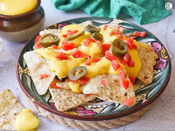 Nachos con queso, cubiertos con jalapeños y tomate picado, listos para disfrutar.