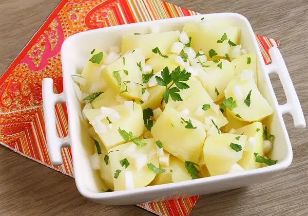 Papas aliñas recién preparadas, con trocitos de cebolla y perejil fresco, listas para disfrutar.
