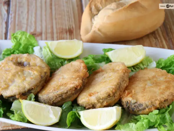 Crujiente merluza a la romana, servida sobre lechuga fresca y gajos de limón. Un plato perfecto para disfrutar.