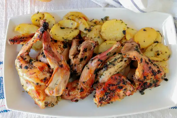 Delicioso conejo al horno con patatas doradas y hierbas aromáticas, listo para servir.