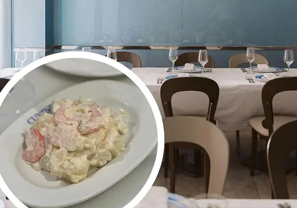 Deliciosa ensaladilla de gambas cremosa, servida en un plato blanco, lista para disfrutar en un restaurante con mesas puestas.