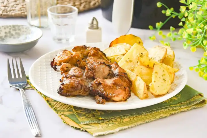 Jugosos contramuslos de pollo dorados con patatas asadas, un plato perfecto para disfrutar.
