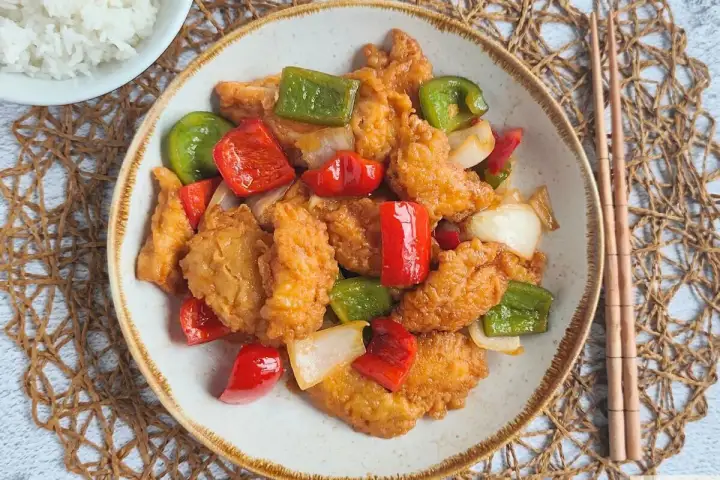 Saborea este delicioso pollo agridulce, crujiente por fuera y tierno por dentro, con pimientos y cebolla. ¡Un festín para tus sentidos!